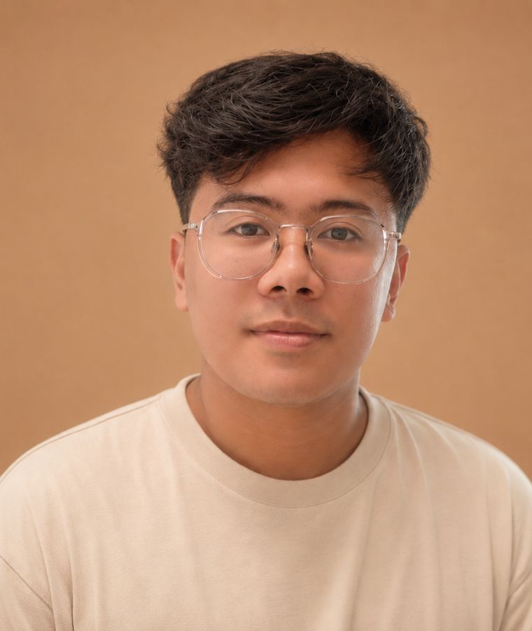Kenneth Villar in glasses and a cream t-shirt against a warm tan backdrop